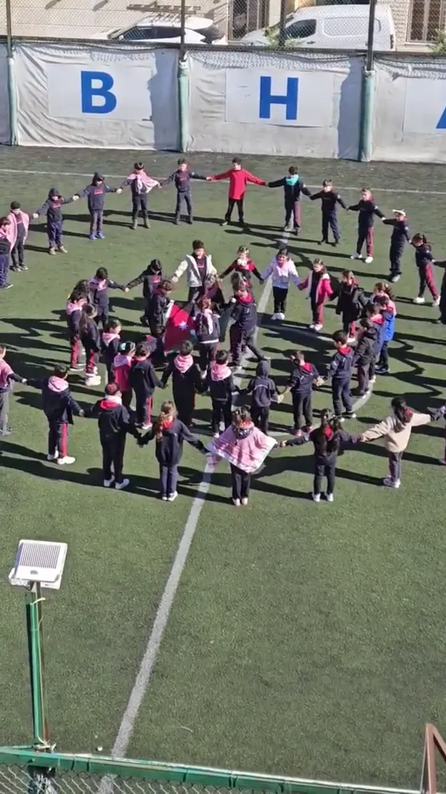 Students forming a display with Jordanian flags on the school field